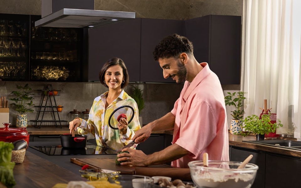 Couple cooking together in a modern lg buit-in kitchen, smiling and preparing fresh ingredients.